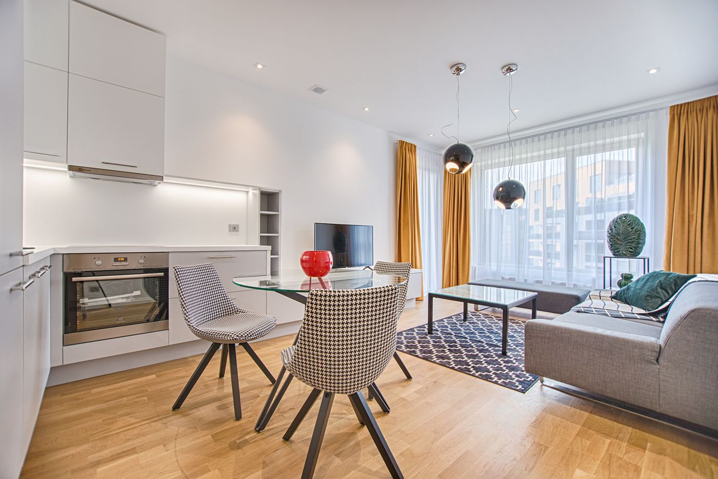 Bright, modern open-plan apartment living room with a sofa, dining area and large windows — the kind of rented home renters insurance protects
